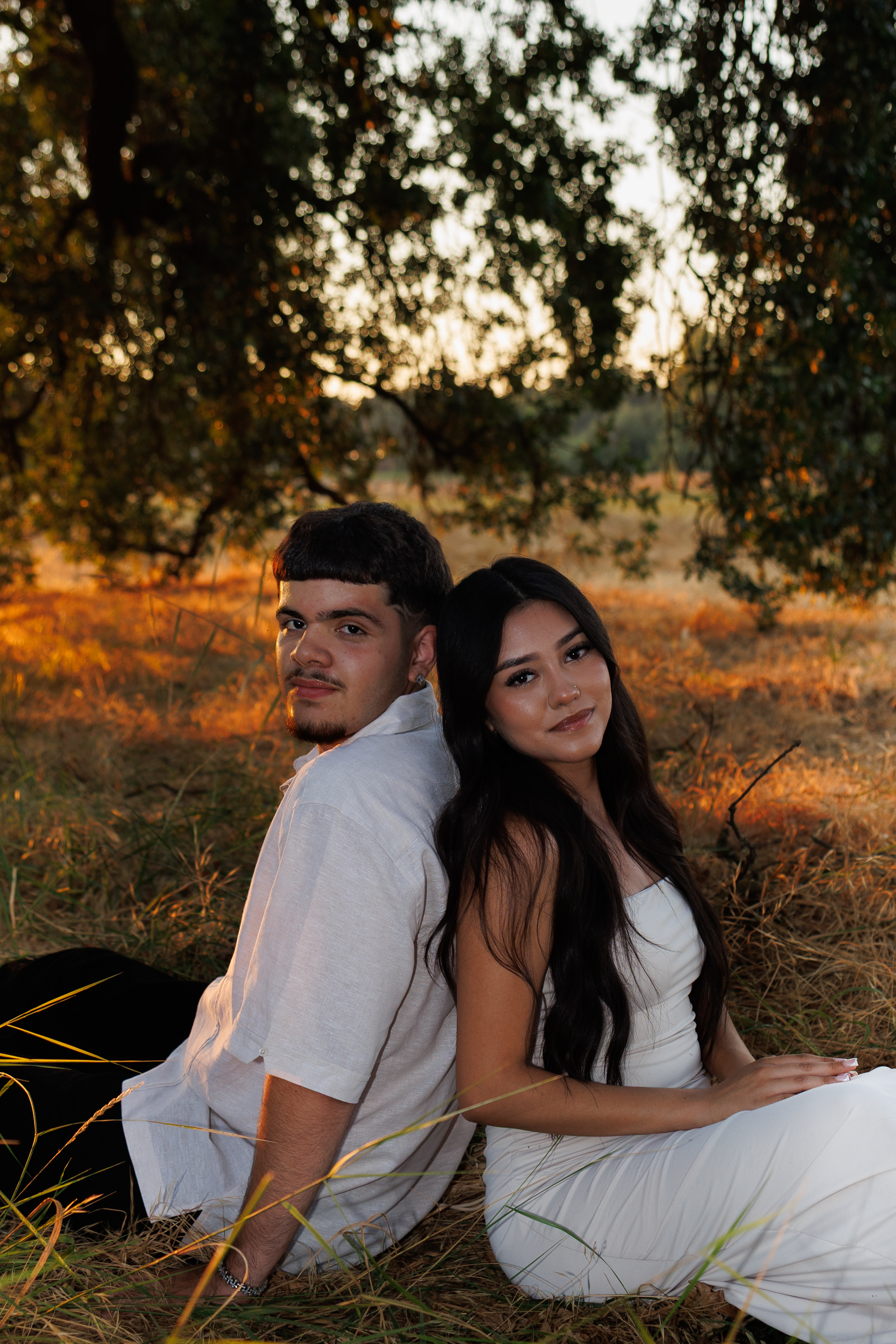 Couple sitting back to back in golden hour field
